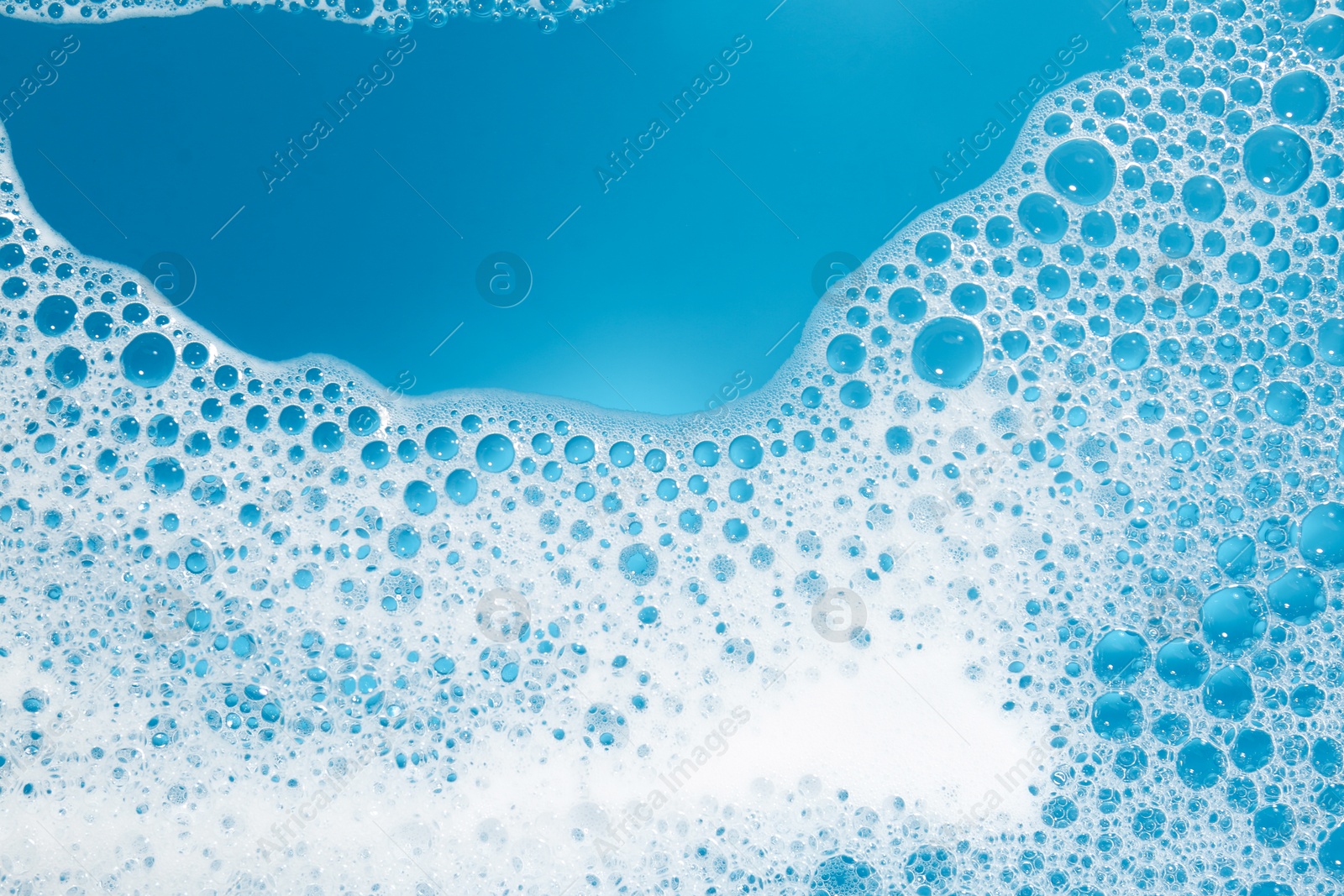 Photo of Detergent foam with bubbles on light blue background, top view