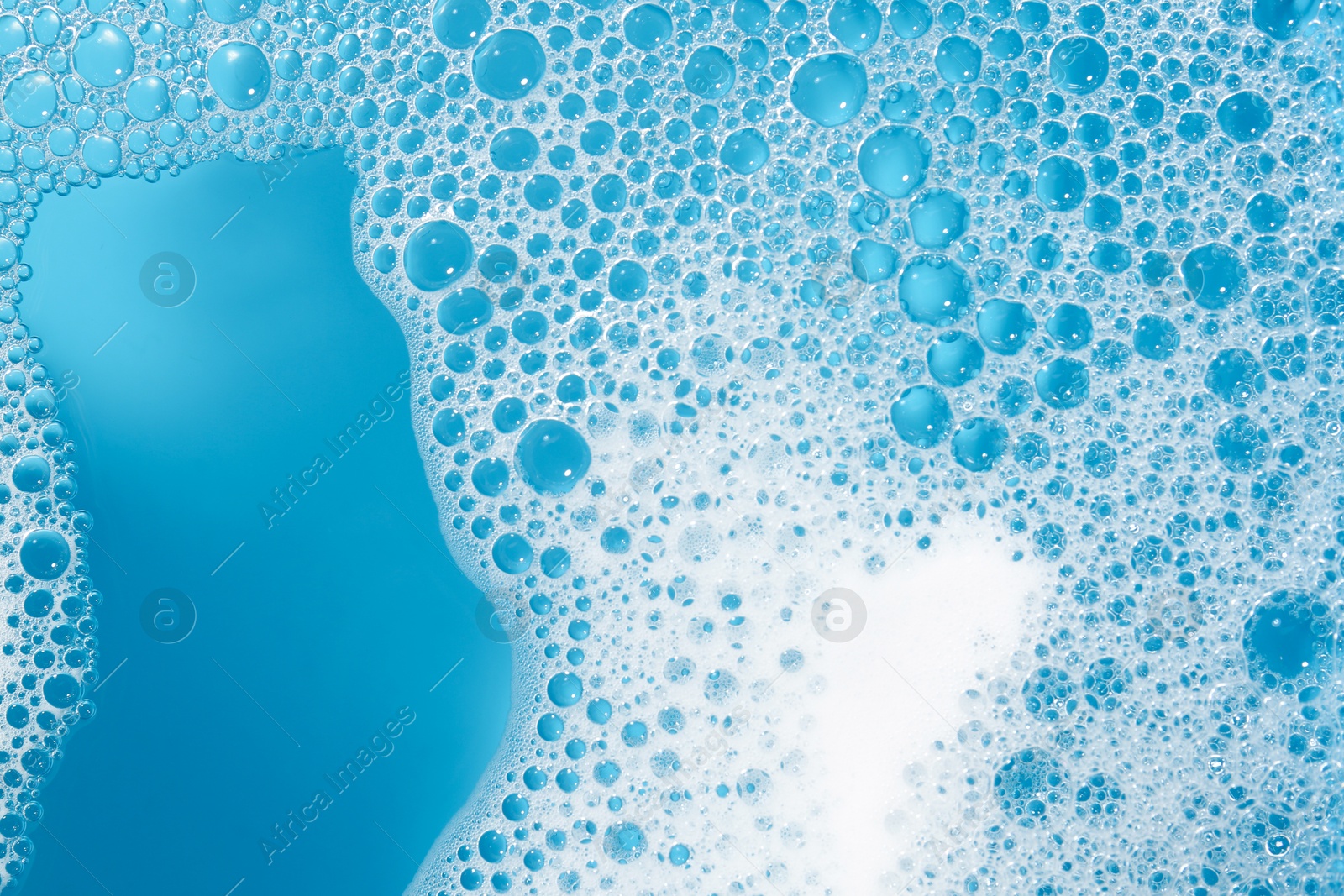 Photo of Detergent foam with bubbles on light blue background, top view