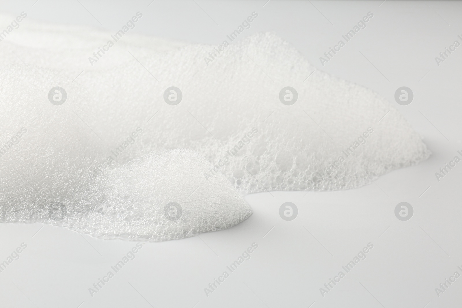 Photo of Detergent foam with bubbles on white background, closeup