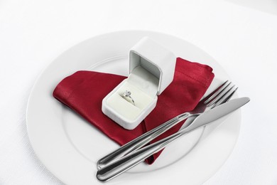 Beautiful engagement ring and setting for romantic dinner on white background, closeup