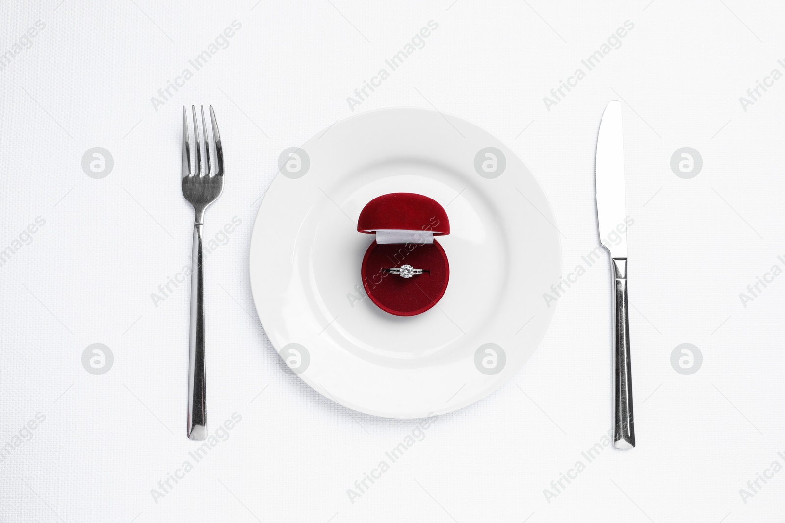 Photo of Beautiful engagement ring and setting for romantic dinner on white background, top view