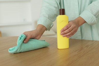 Photo of Woman polishing wooden table at home, closeup