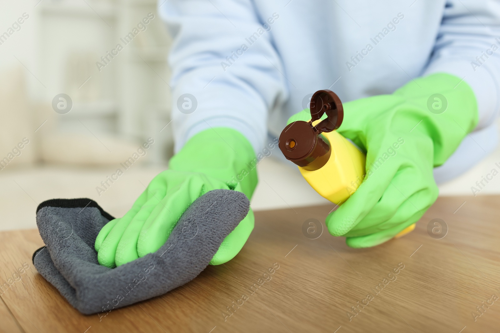 Photo of Woman polishing wooden table at home, closeup