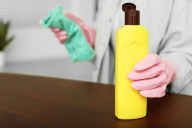 Photo of Woman polishing wooden table at home, closeup