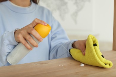 Photo of Woman polishing wooden table at home, closeup