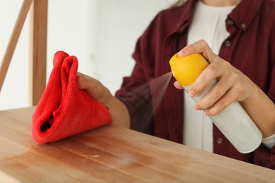 Photo of Woman polishing wooden table at home, closeup