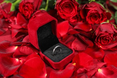 Photo of Engagement ring in box, rose flowers and petals, closeup. Romantic proposal