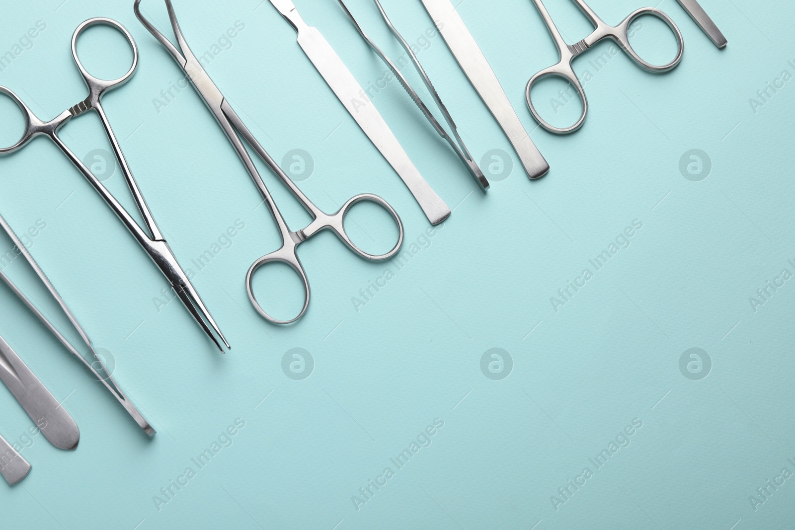 Photo of Different surgical tools on turquoise background, flat lay. Space for text