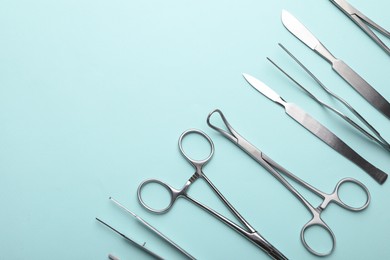 Photo of Different surgical tools on turquoise background, flat lay. Space for text