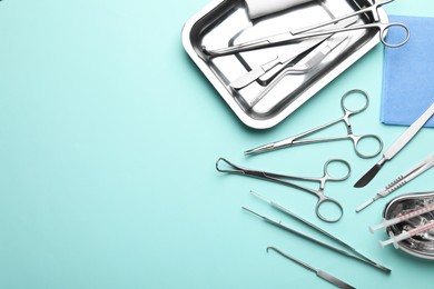 Photo of Different surgical tools on turquoise background, flat lay. Space for text