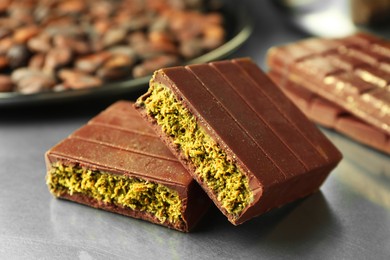 Photo of Pieces of tasty Dubai chocolate with pistachios and knafeh on grey table, closeup