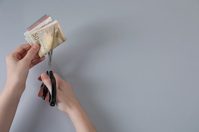 Photo of Woman cutting euro banknotes on gray background, top view. Space for text