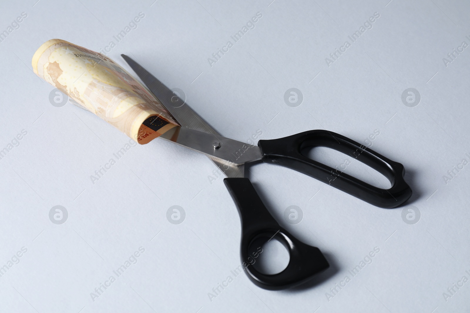 Photo of Scissors with euro banknote on gray background