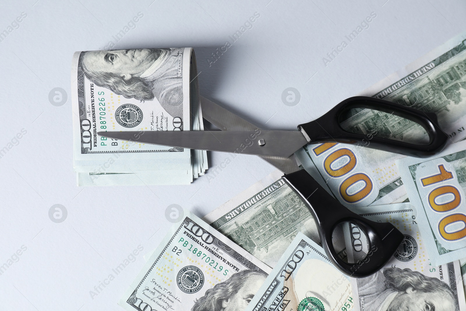 Photo of Dollar banknotes and scissors on gray background, flat lay