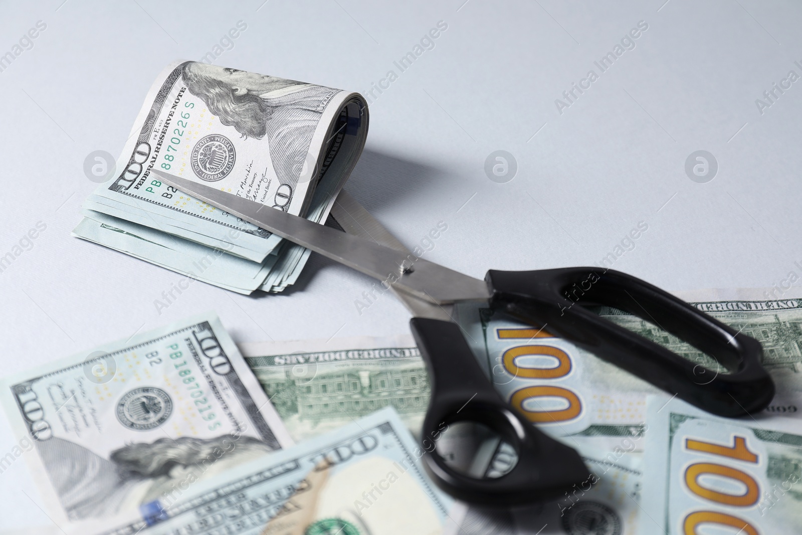 Photo of Dollar banknotes and scissors on gray background, closeup