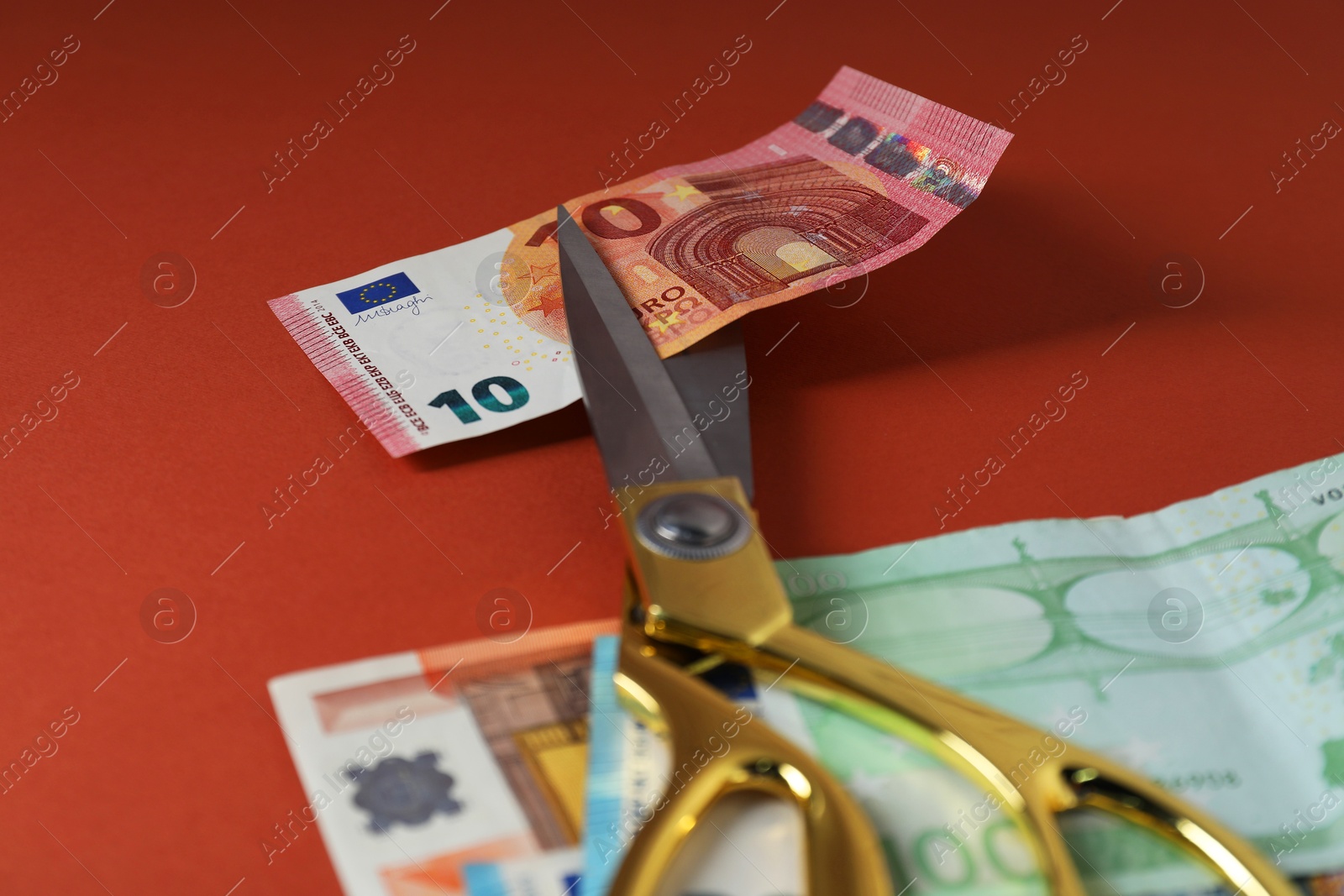 Photo of Euro banknotes and scissors on brown background, closeup