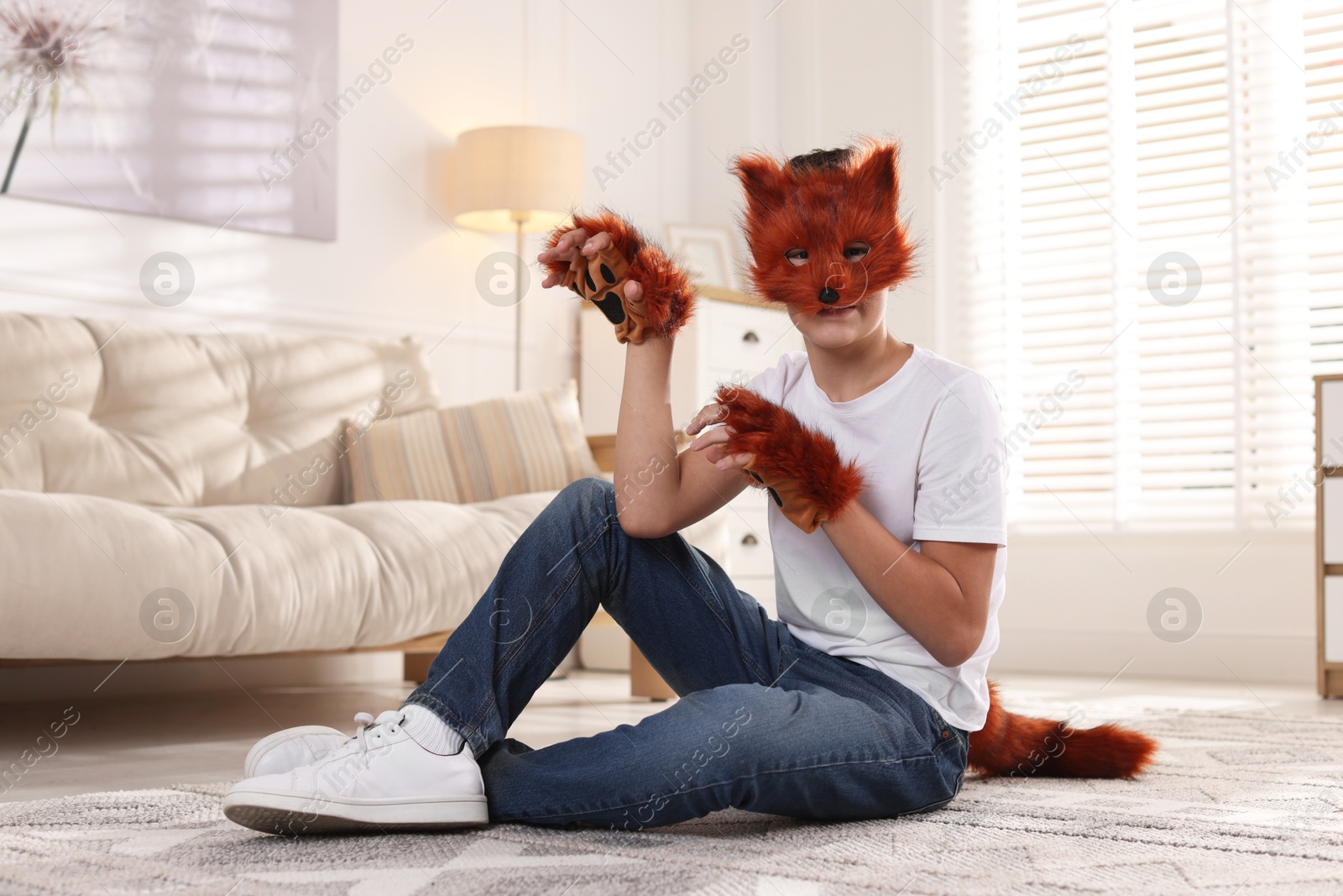 Photo of Quadrobics. Boy wearing fox mask, gloves and tail on floor at home