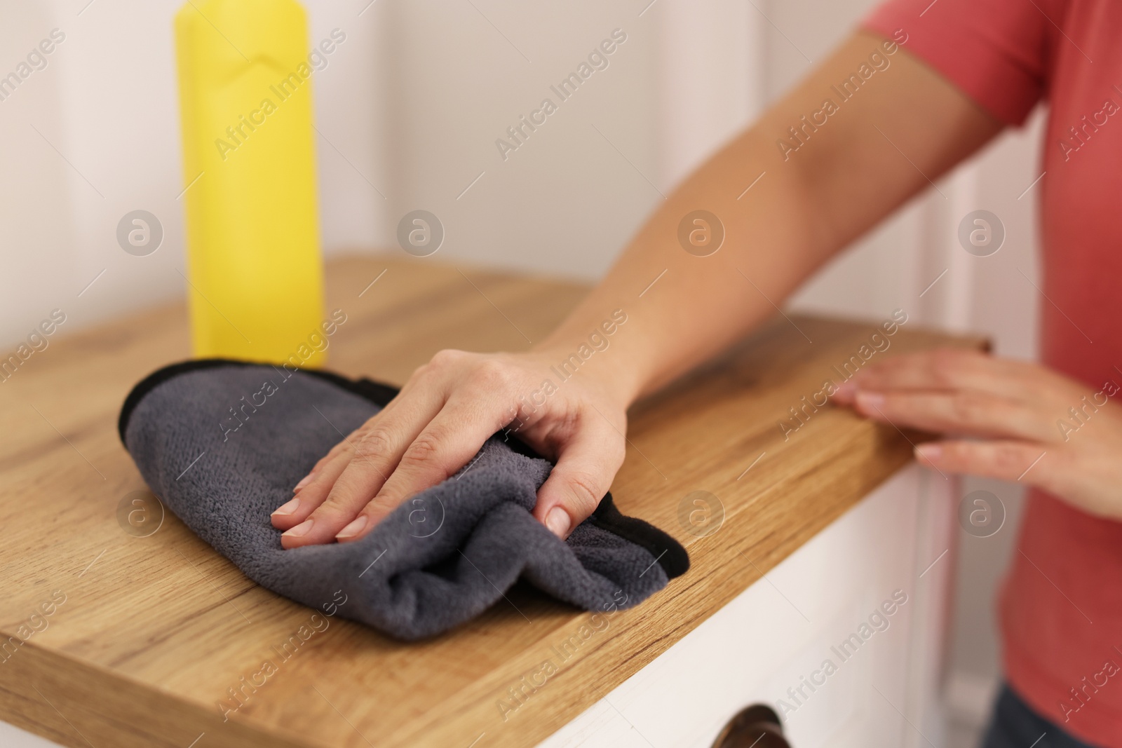 Photo of Woman polishing wooden cabinet with rag at home, closeup