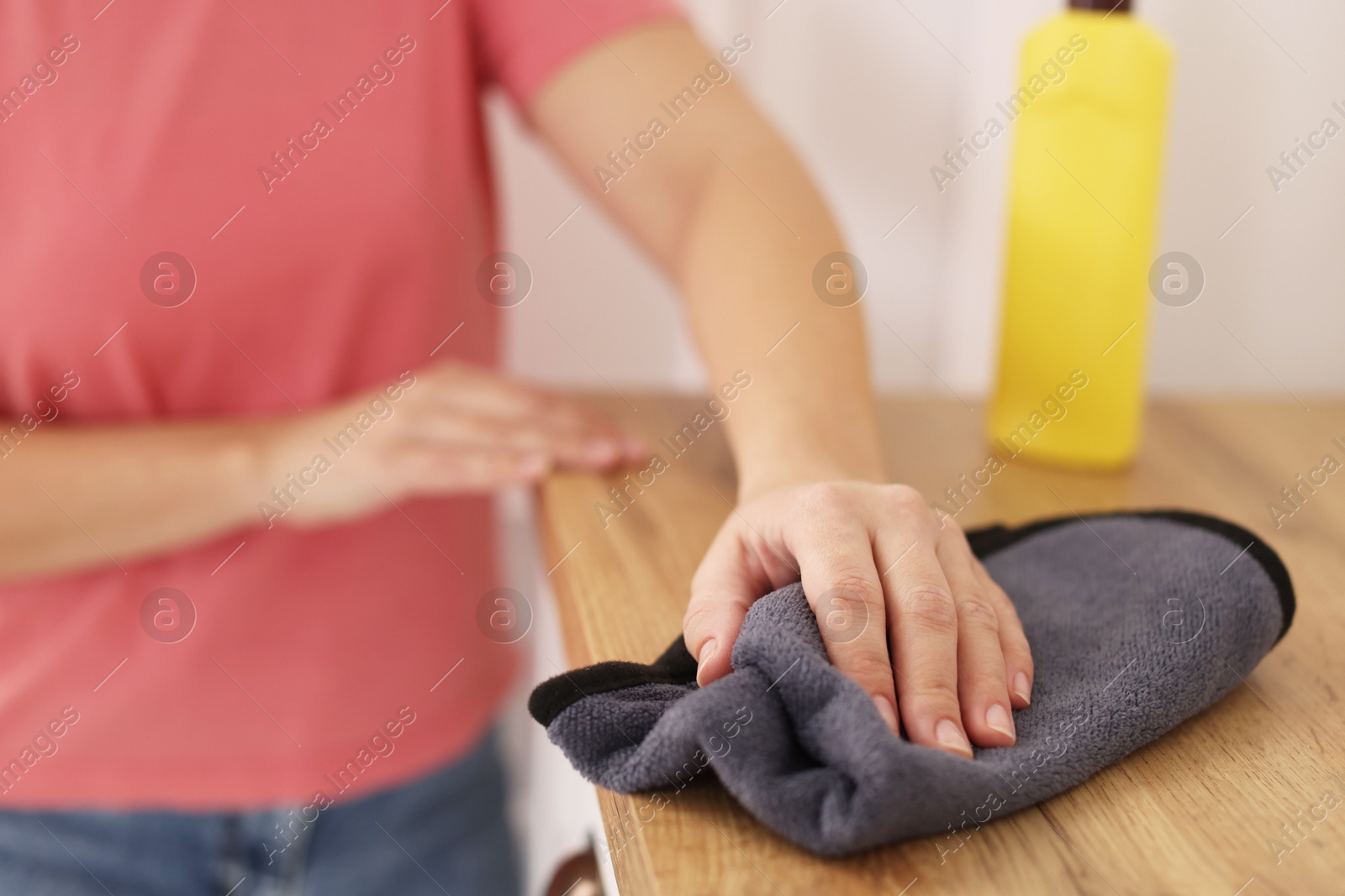 Photo of Woman polishing wooden cabinet with rag at home, closeup