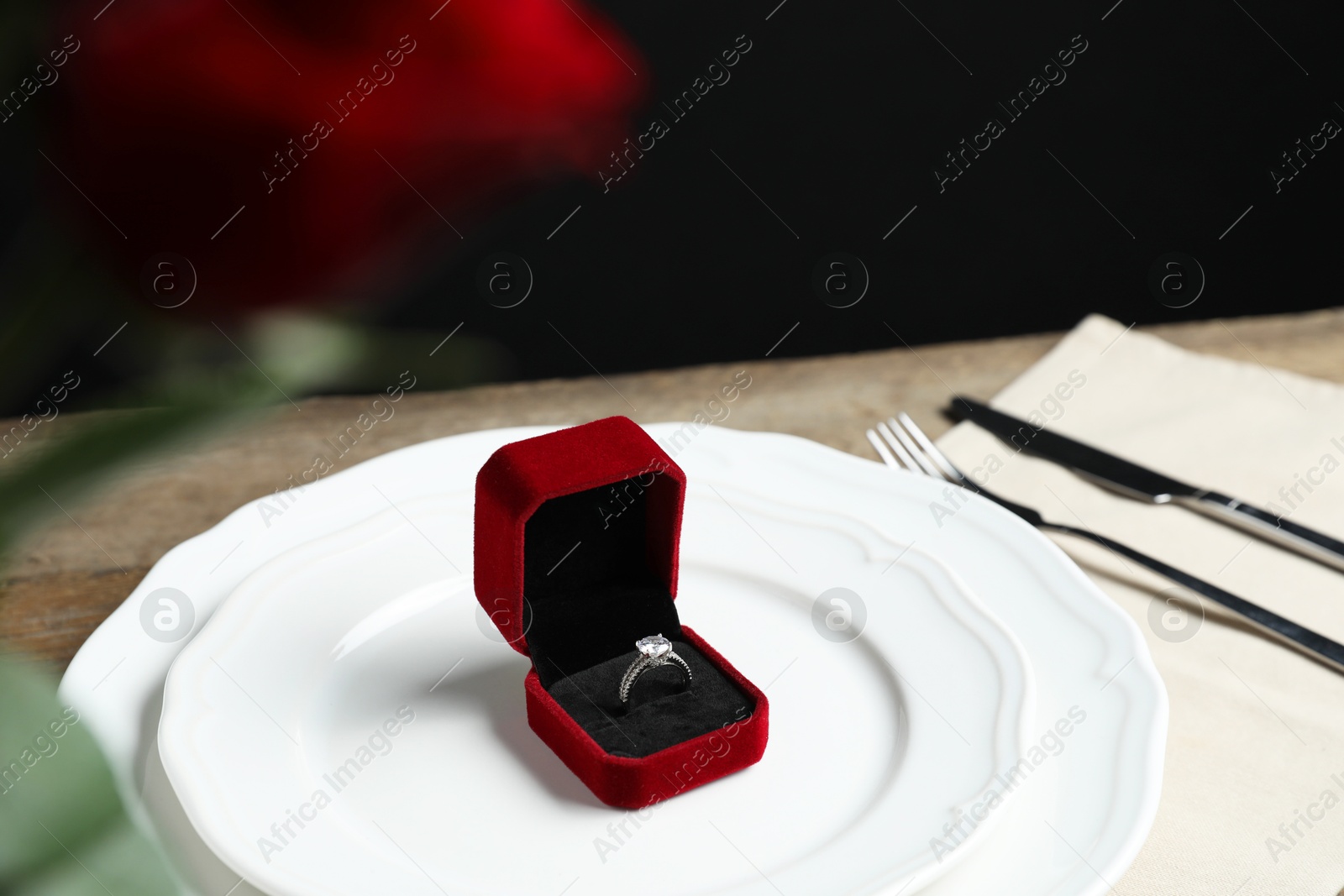 Photo of Beautiful setting for romantic dinner and engagement ring on wooden table