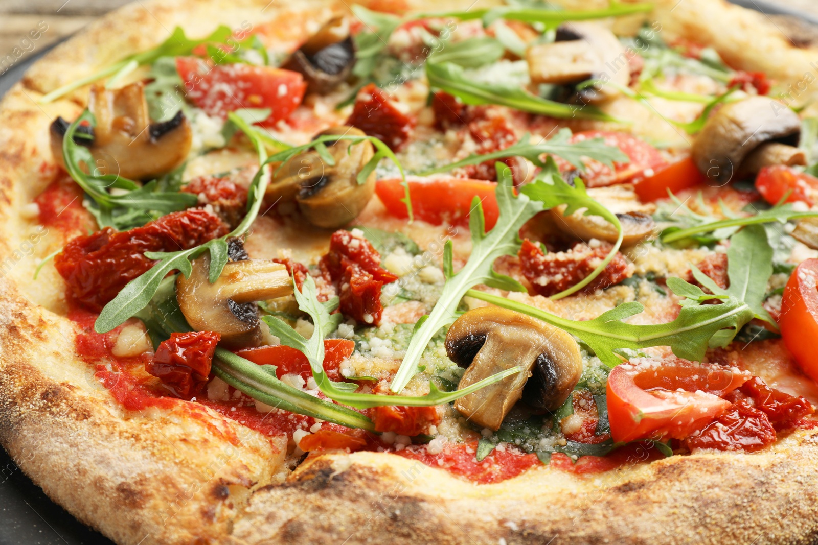 Photo of Tasty pizza with mushrooms, tomatoes and arugula on table, closeup