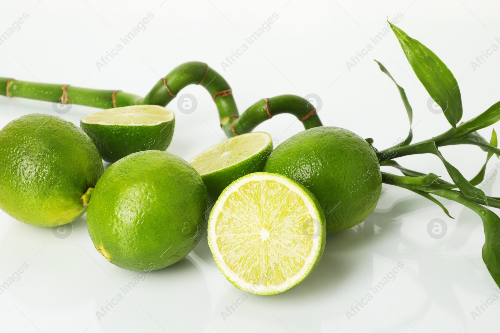 Photo of Fresh limes and bamboo stem on mirror surface