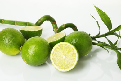 Photo of Fresh limes and bamboo stem on mirror surface