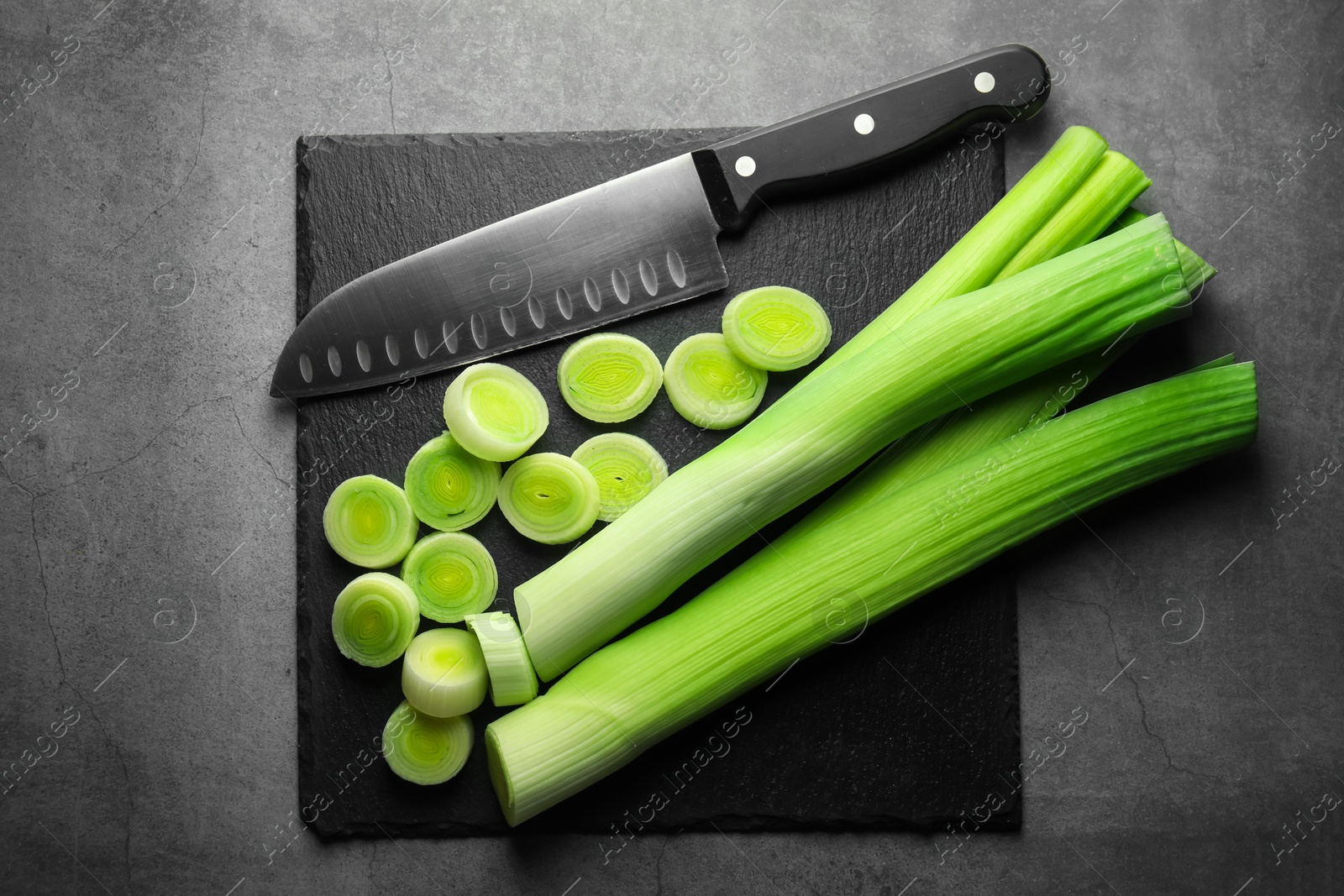 Photo of Chopped leeks and knife on grey table, top view