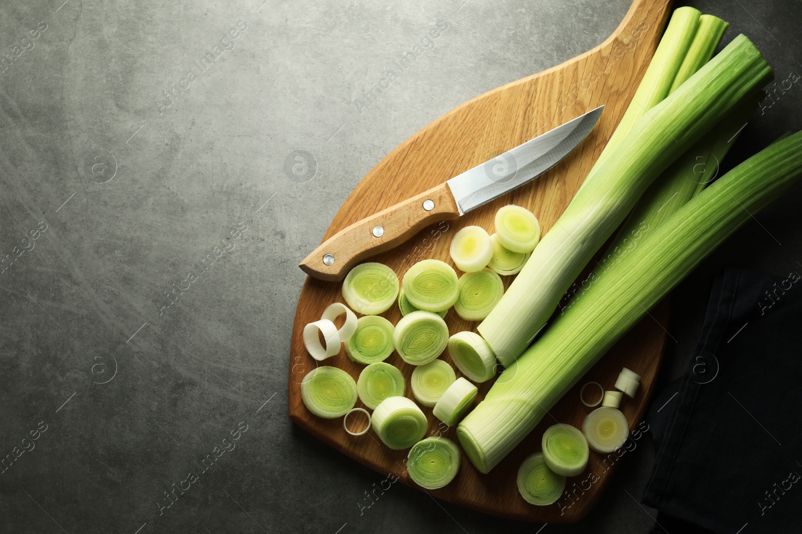 Photo of Chopped leeks and knife on grey table, top view. Space for text