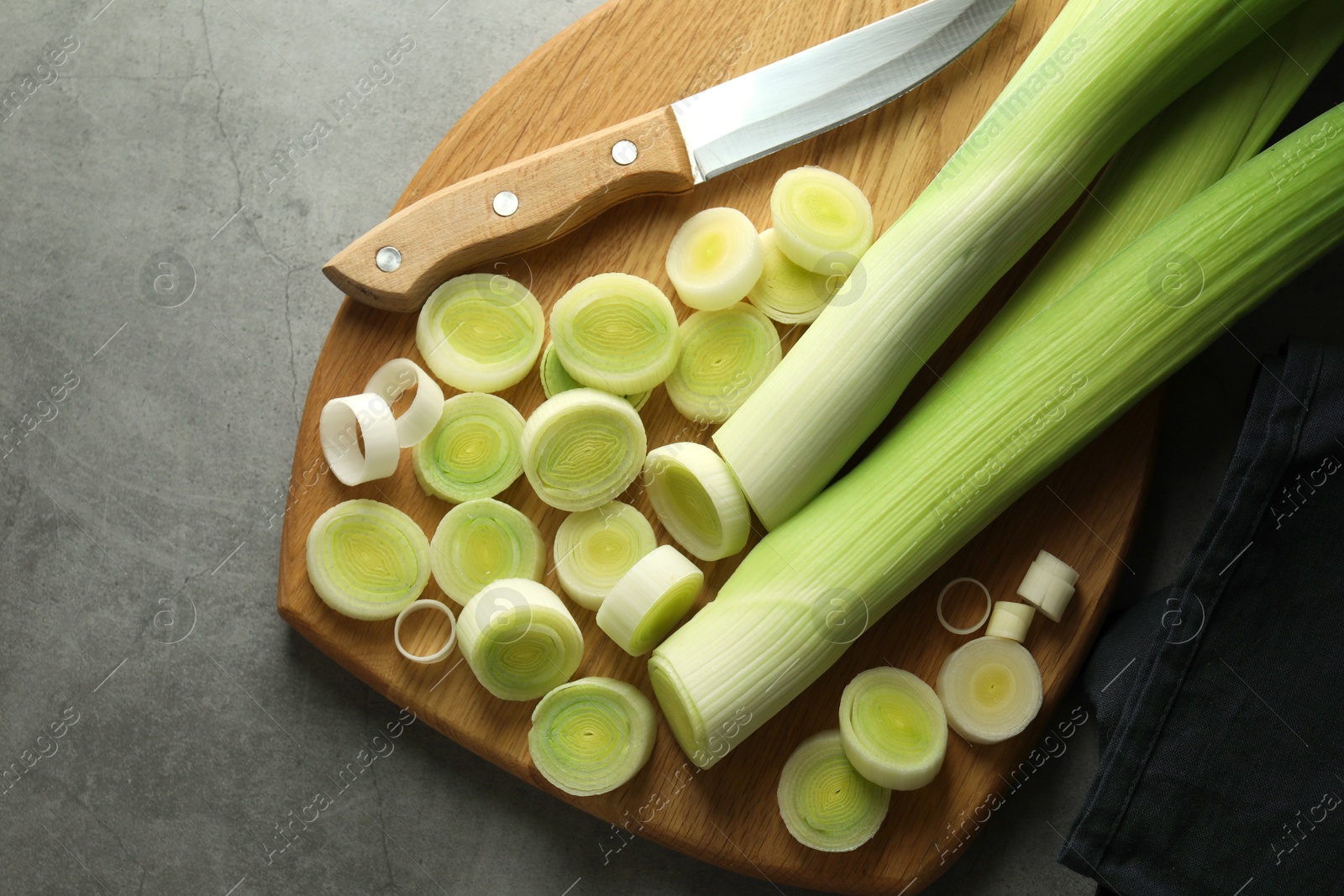 Photo of Chopped leeks and knife on grey table, top view