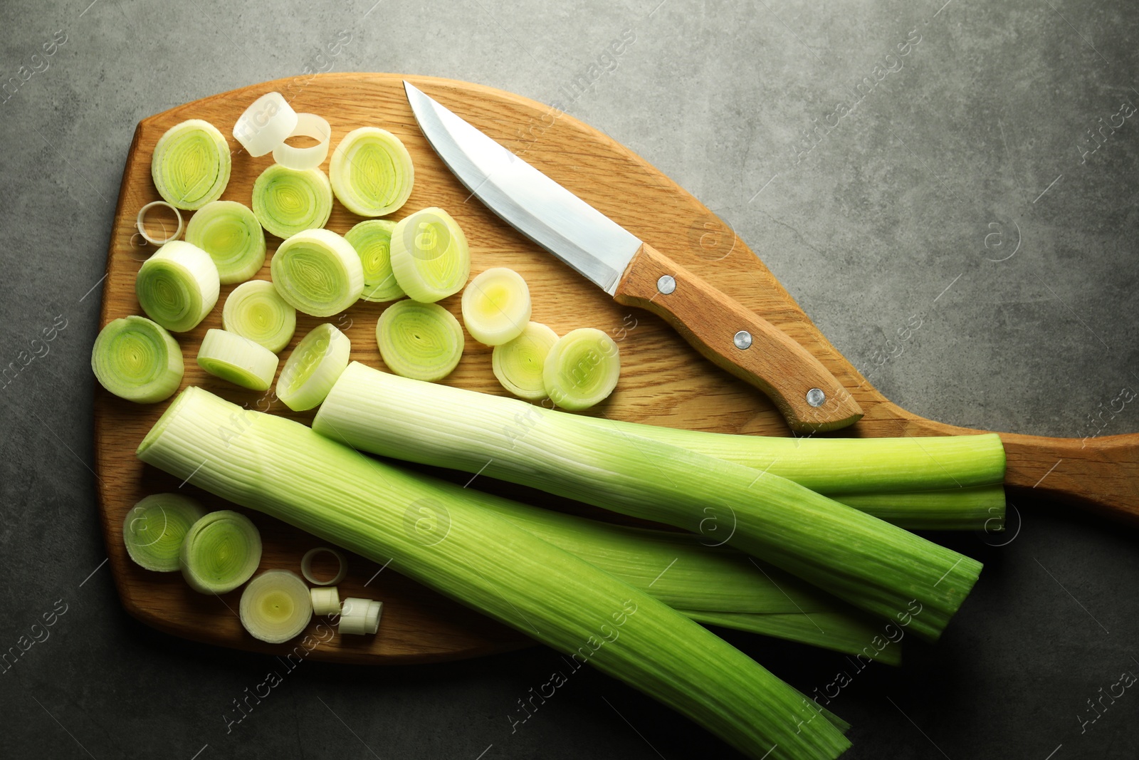 Photo of Chopped leeks and knife on grey table, top view