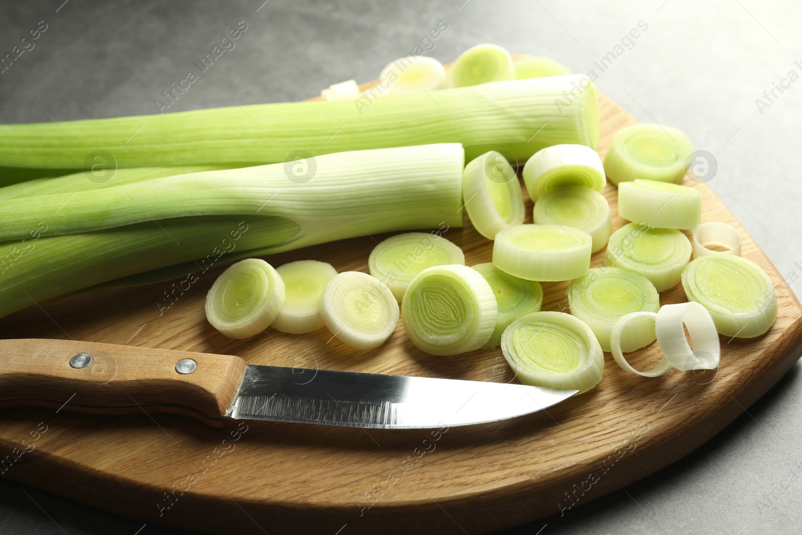 Photo of Chopped leeks and knife on grey table, closeup