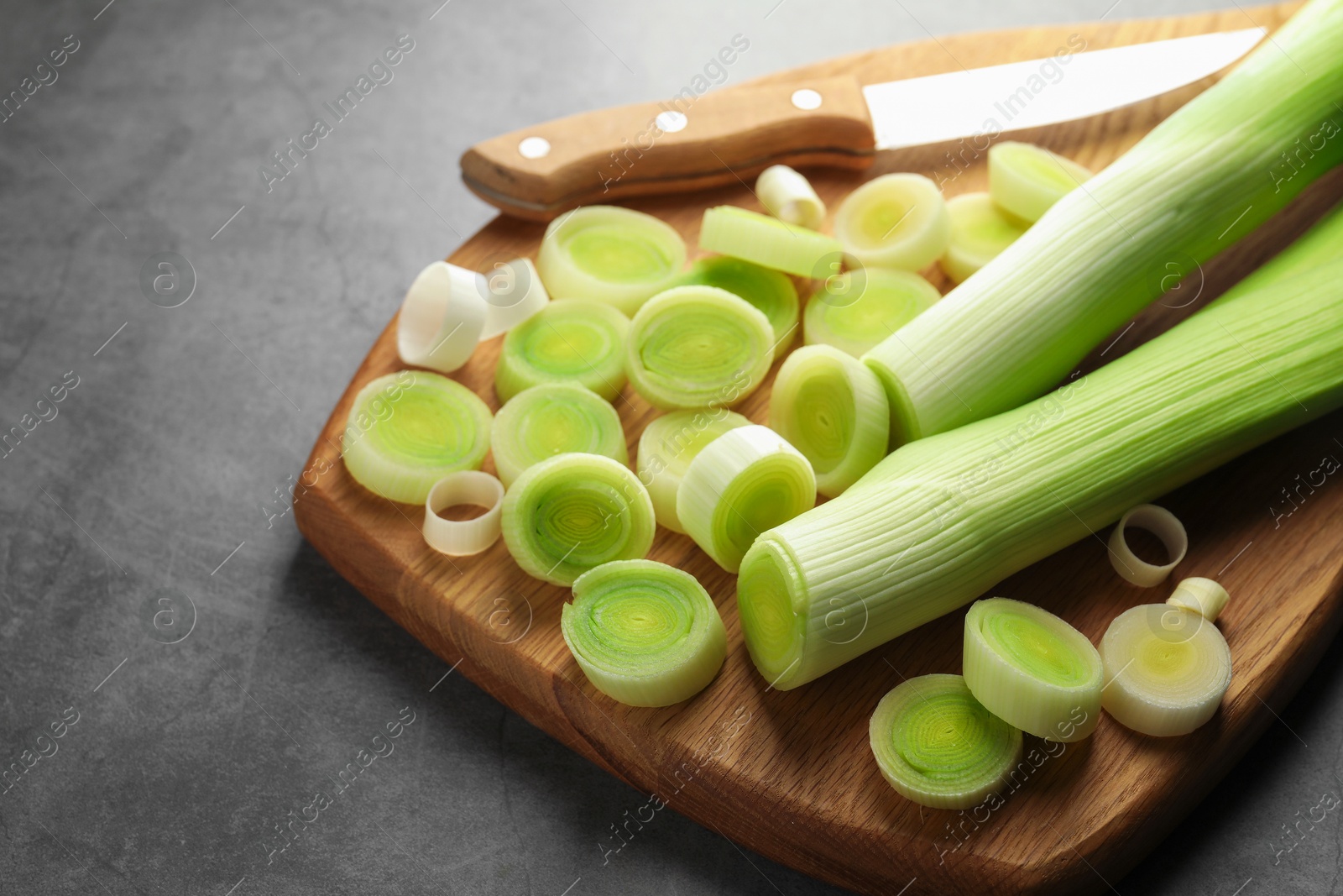 Photo of Chopped leeks and knife on grey table, closeup