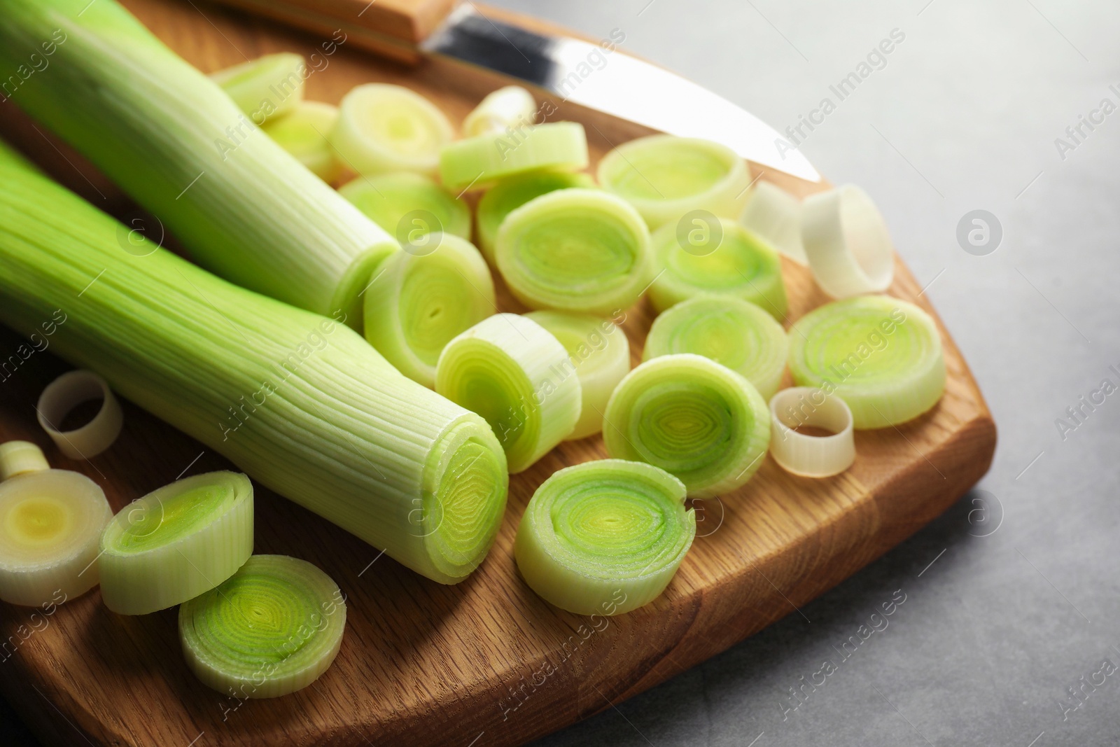 Photo of Chopped leeks and knife on grey table, closeup