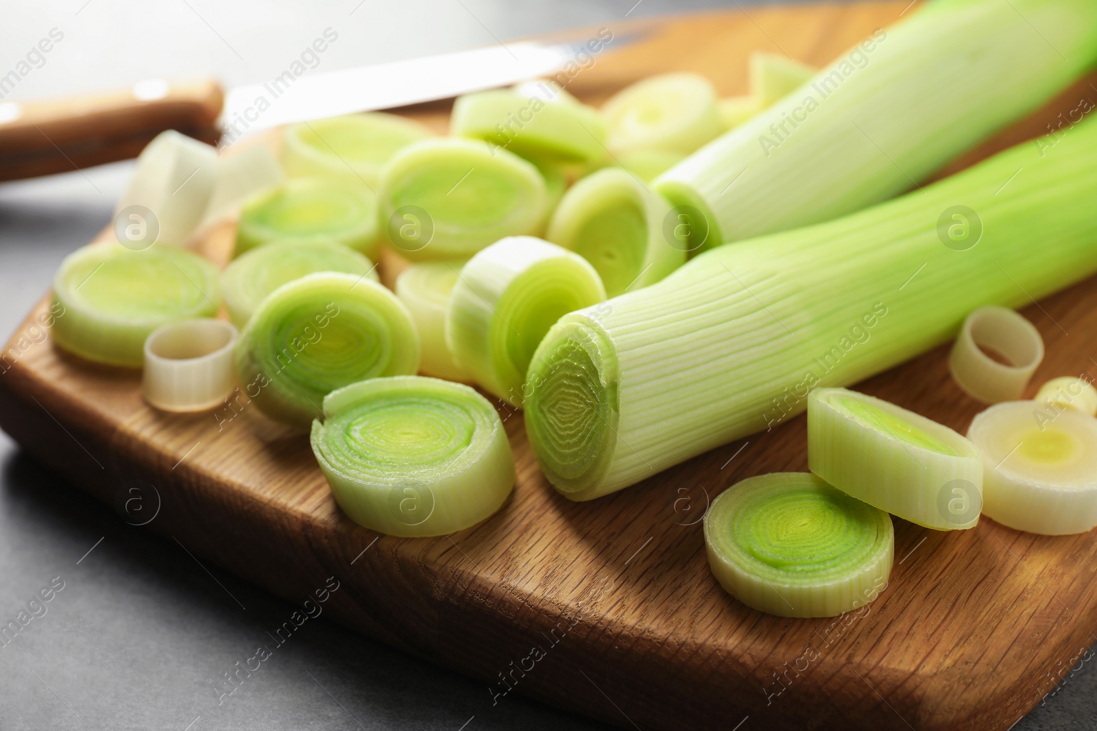 Photo of Chopped leeks and knife on grey table, closeup