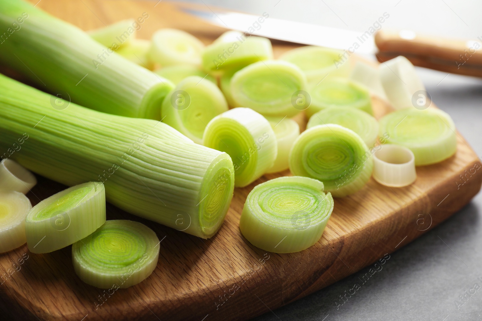 Photo of Chopped leeks and knife on grey table, closeup