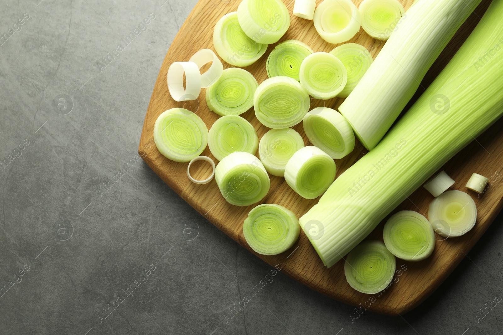 Photo of Fresh cut leeks on grey table, top view. Space for text