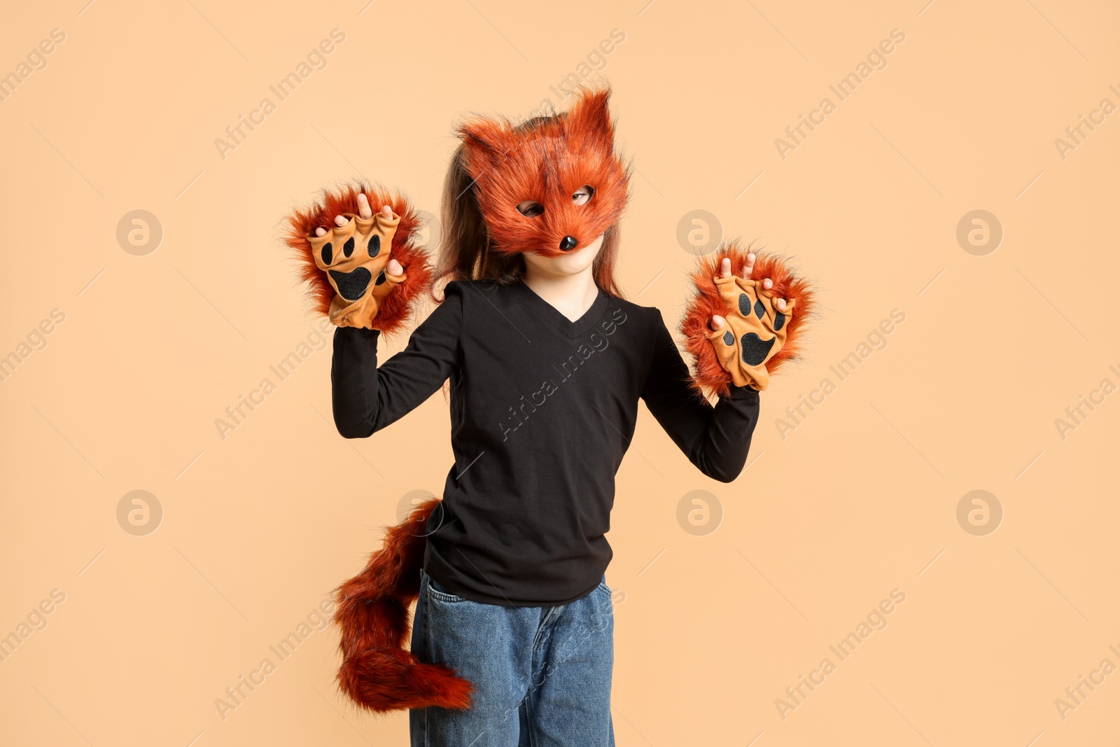 Photo of Quadrobics. Girl wearing fox mask, tail and gloves on beige background