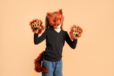 Photo of Quadrobics. Girl wearing fox mask, tail and gloves on beige background