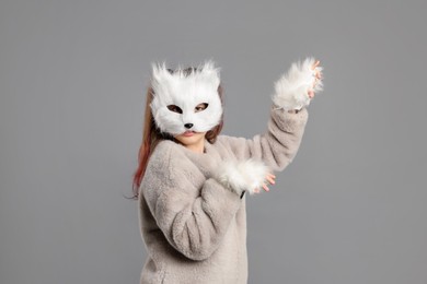 Quadrobics. Girl wearing cat mask and gloves on grey background