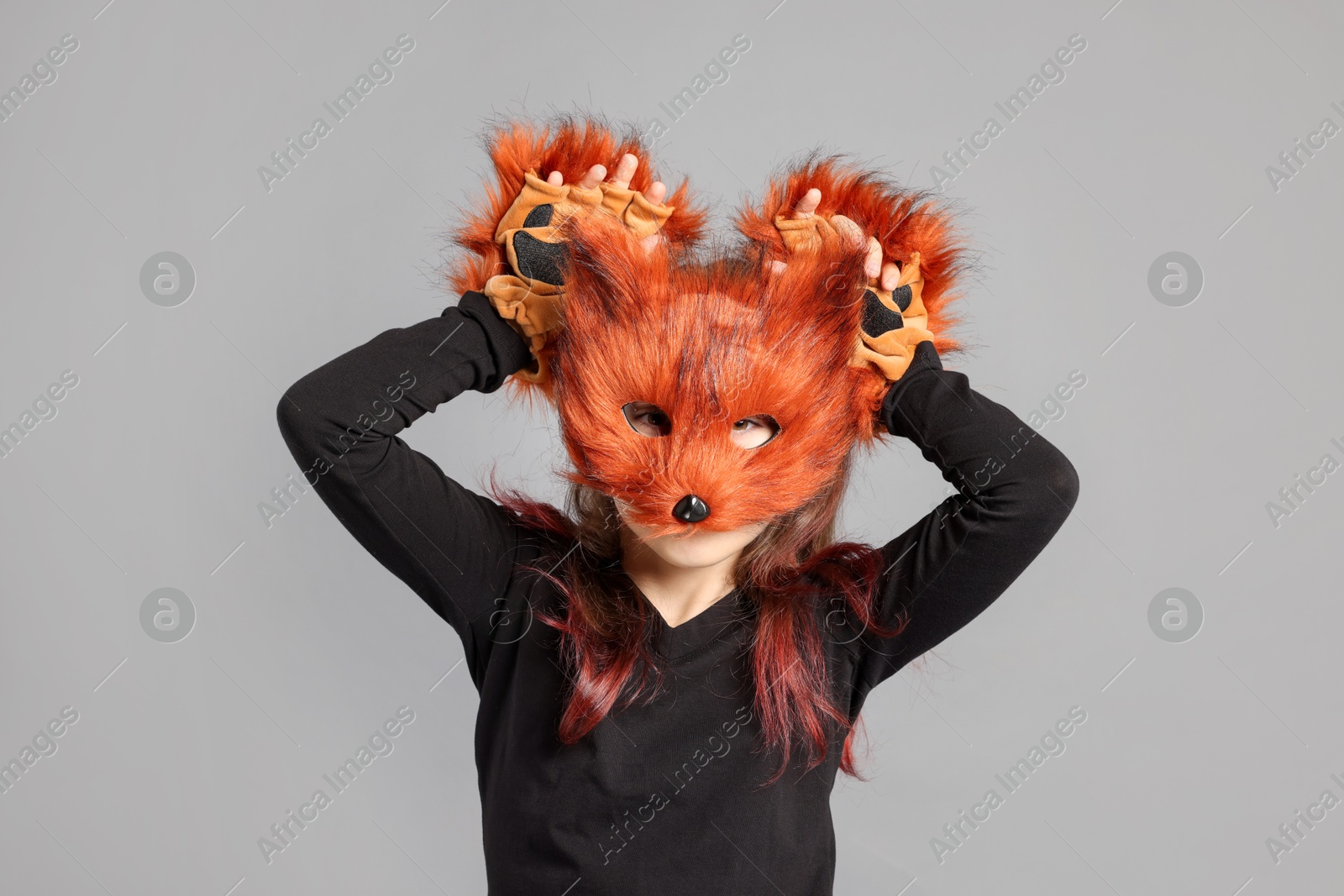 Photo of Quadrobics. Girl wearing fox mask and gloves on grey background