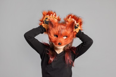 Photo of Quadrobics. Girl wearing fox mask and gloves on grey background