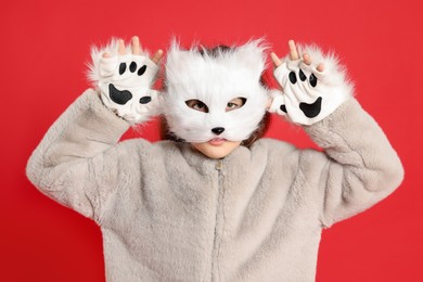 Photo of Quadrobics. Girl wearing cat mask and gloves on red background