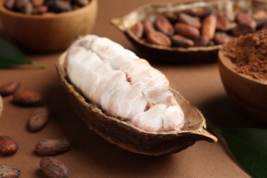 Photo of Cocoa pod with beans and powder on brown background, closeup