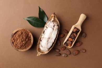 Photo of Cocoa pod with beans and powder on brown background, flat lay