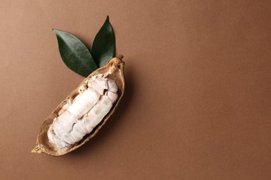 Photo of Cocoa pod with beans on brown background, top view. Space for text