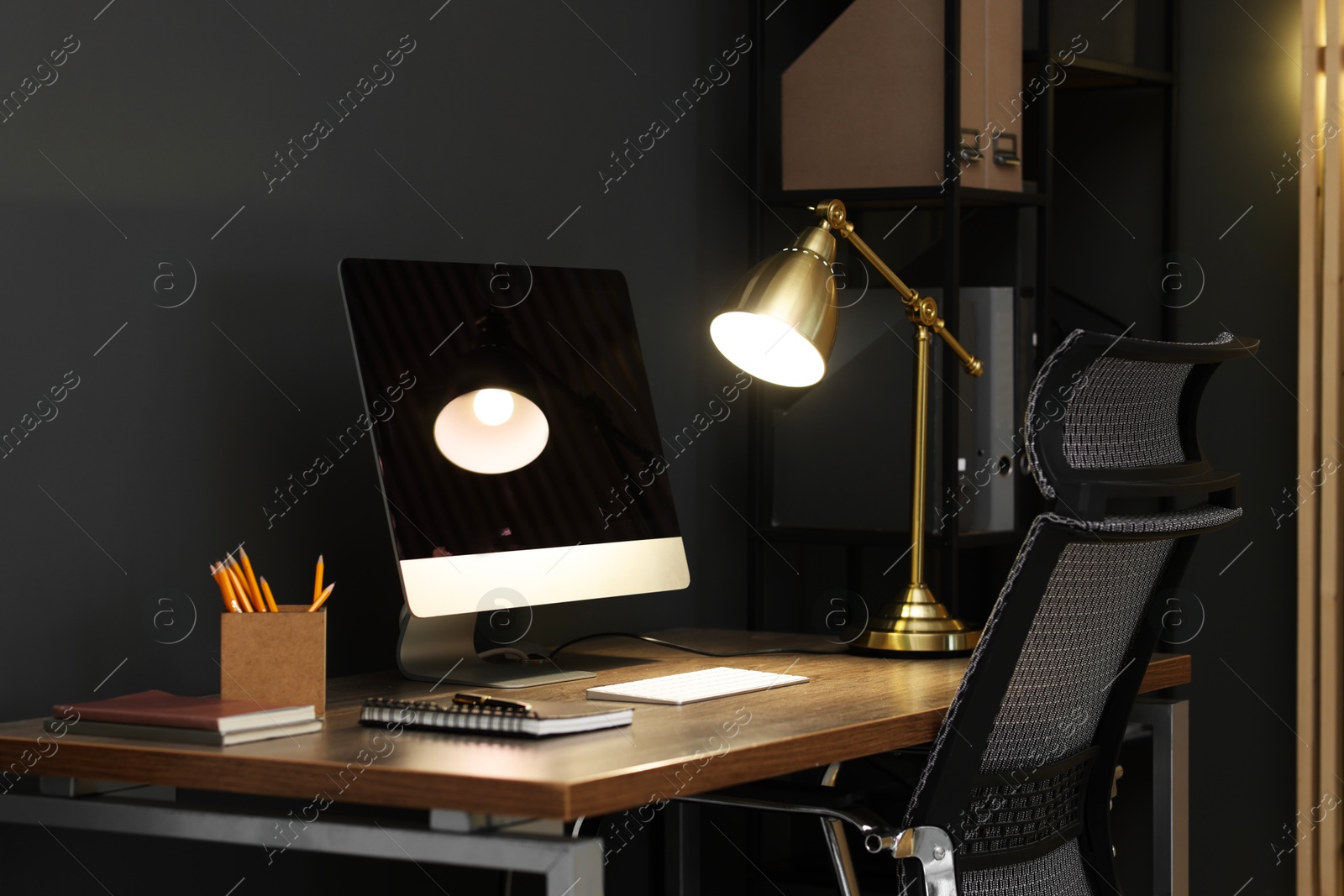 Comfortable workplace with computer and lamp on wooden desk in home office Photo of Comfortable workplace with computer and lamp on wooden desk in home office