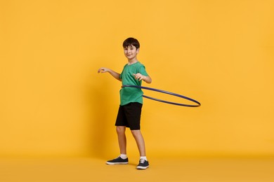 Photo of Boy exercising with hula hoop on yellow background