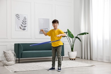 Photo of Boy exercising with hula hoop at home