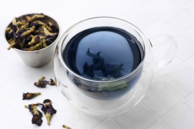 Photo of Delicious butterfly pea flower tea on white tiled table, closeup